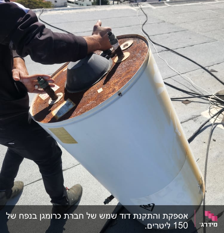 אדם מחזיק דוד שמש חלוד על גג שטוח